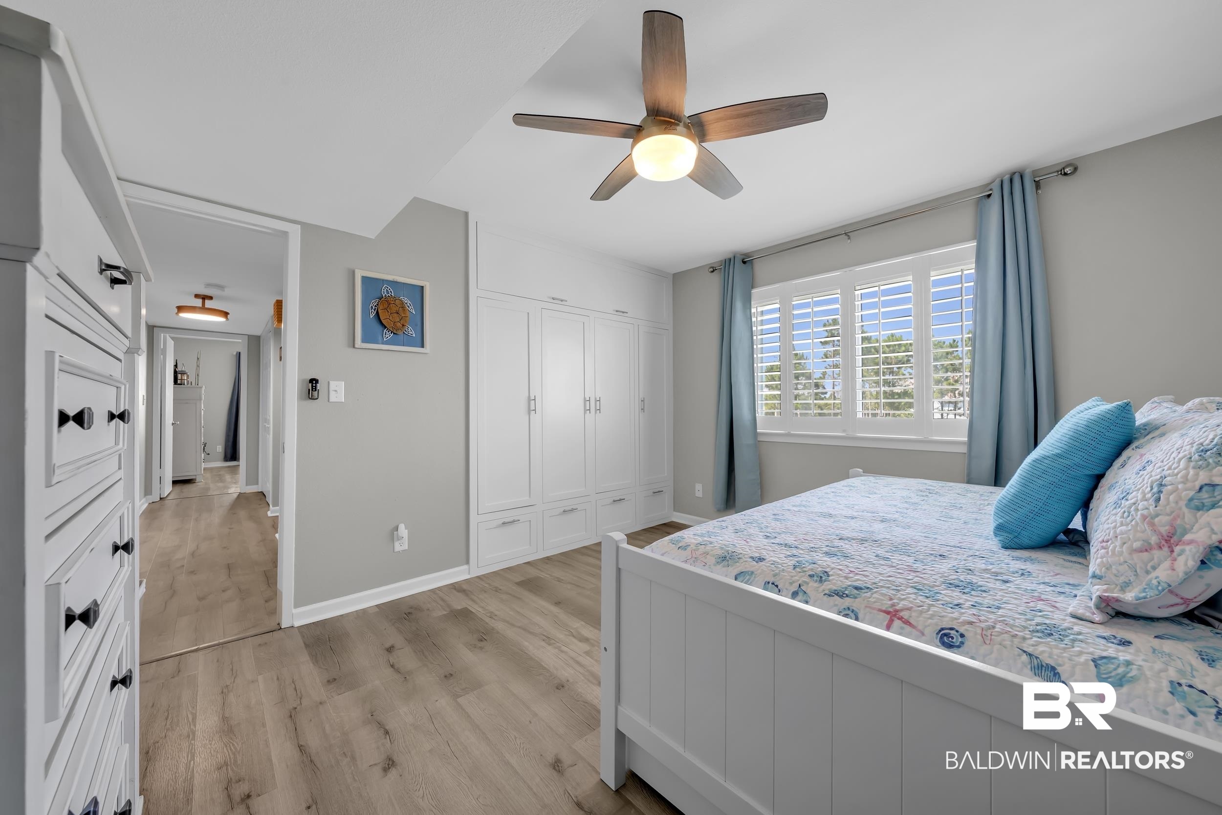14100 River Road, Unit 211 Pensacola, FL 32507 - Photo 34 of 56 Bedroom featuring light wood-finish flooring, built-in cabinetry, white window shutters, and a ceiling fan with integrated lighting