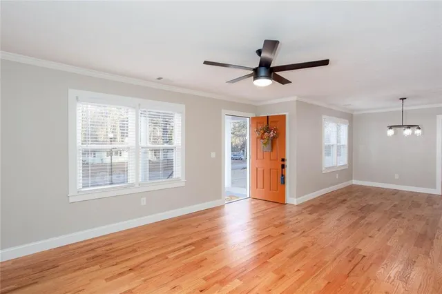 a view of an empty room with wooden floor and a window