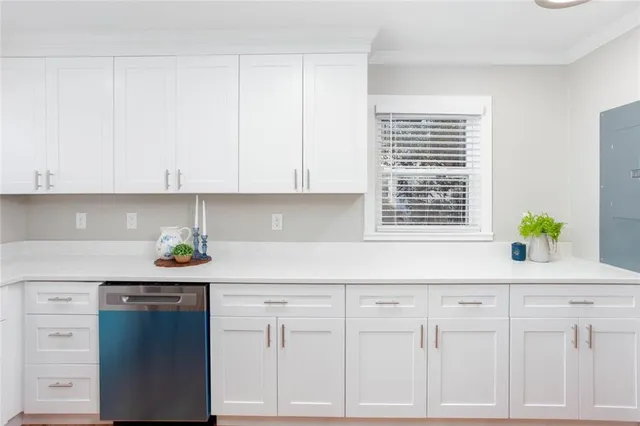 a kitchen with white cabinets and a window