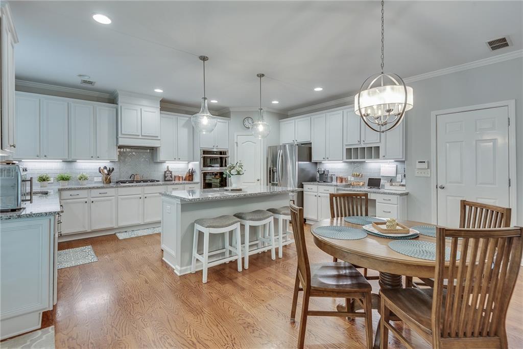 3315 Thimbleberry Trail Dacula, GA 30019 - Photo 17 of 59 a kitchen with stainless steel appliances kitchen island granite countertop a table chairs and a refrigerator