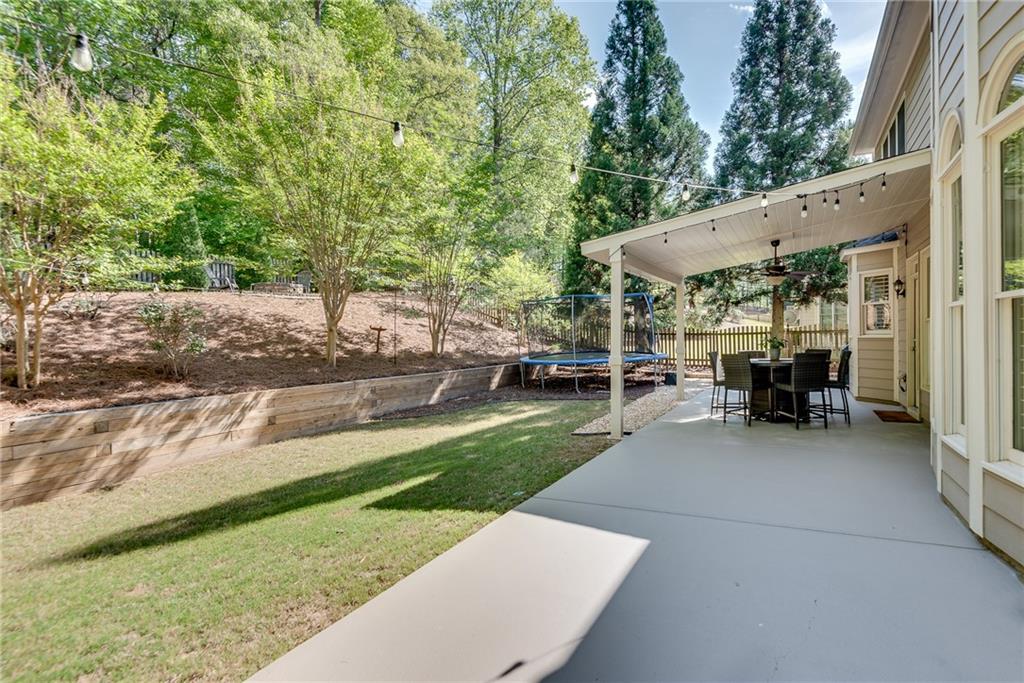 3315 Thimbleberry Trail Dacula, GA 30019 - Photo 48 of 59 a view of a patio with table and chairs under an umbrella with large trees
