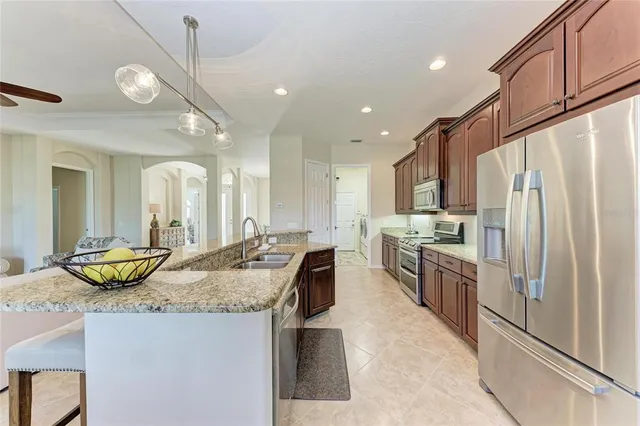 a large kitchen with granite countertop a large counter top appliances and cabinets