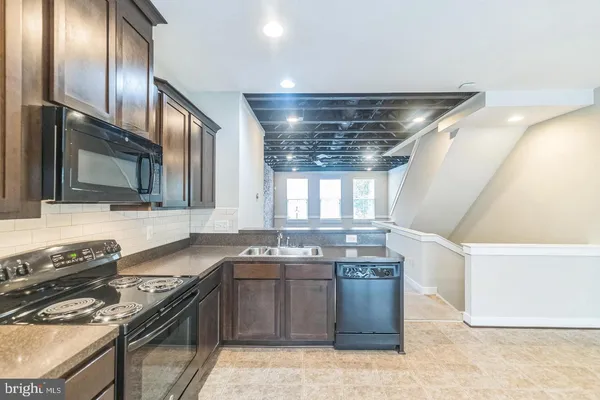 a kitchen with stainless steel appliances granite countertop a stove a refrigerator a sink a dining table and chairs