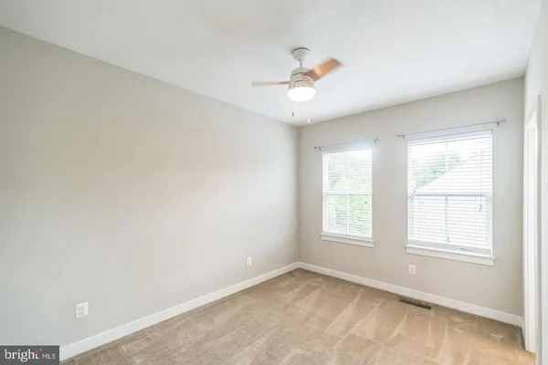 an empty room with windows and chandelier fan