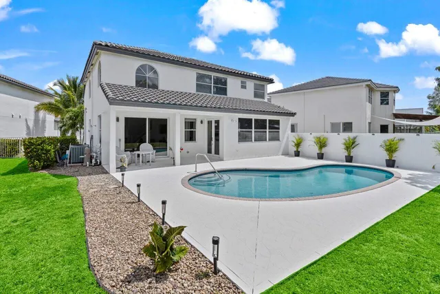a view of a house with a big yard plants and large trees