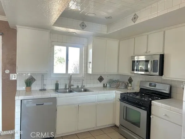 a kitchen with stainless steel appliances granite countertop a sink stove oven and white cabinets