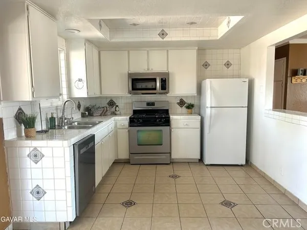 a kitchen with a refrigerator a stove top oven a sink and cabinets