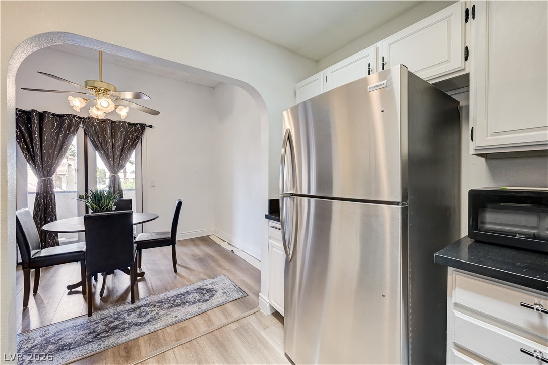 1751 East Reno Avenue, Unit 228 Las Vegas, NV 89119 - Photo 17 of 39 A well-lit dining area flows into a kitchen featuring contemporary cabinetry and a stainless steel refrigerator.