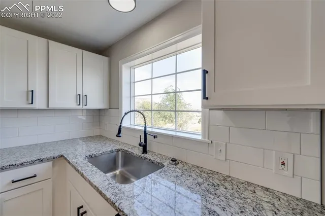 a kitchen with granite countertop a sink stove and cabinets