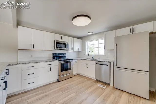 a kitchen with granite countertop white cabinets and stainless steel appliances