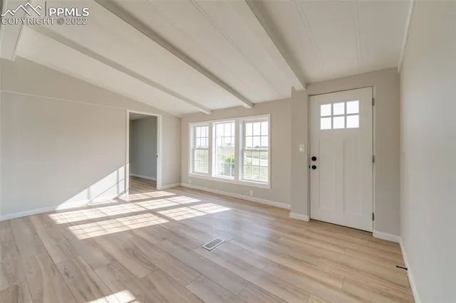 a view of an empty room with wooden floor and a window