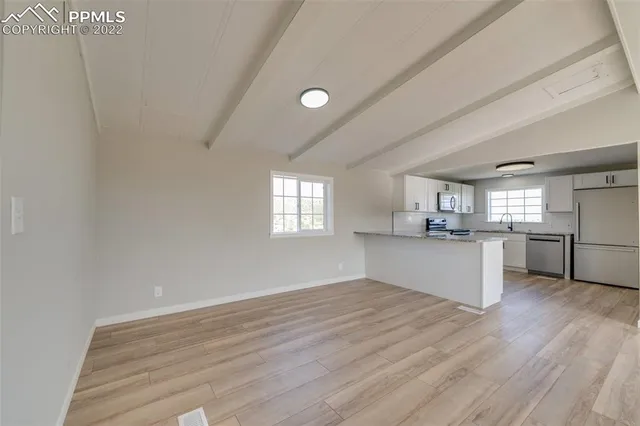 a view of a kitchen with wooden floor and windows