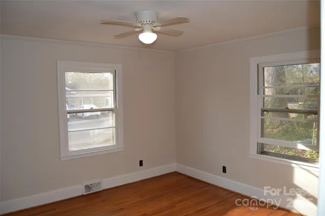 a view of an empty room with a window and wooden floor