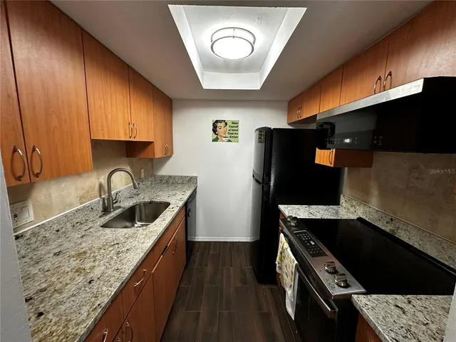 a kitchen with granite countertop a stove and a sink