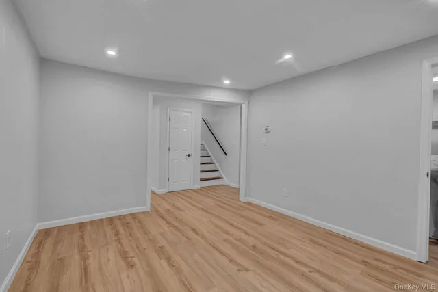 a view of an empty room with wooden floor and stairs