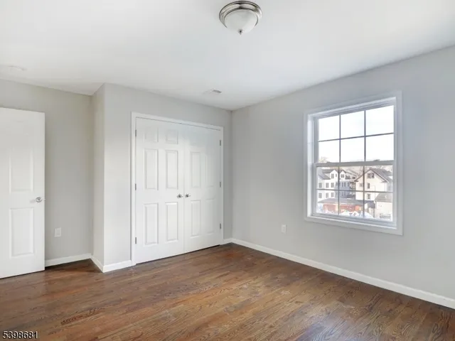 an empty room with wooden floor cabinet and windows