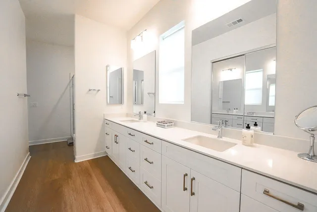 a bathroom with a double vanity sink and mirror with shower
