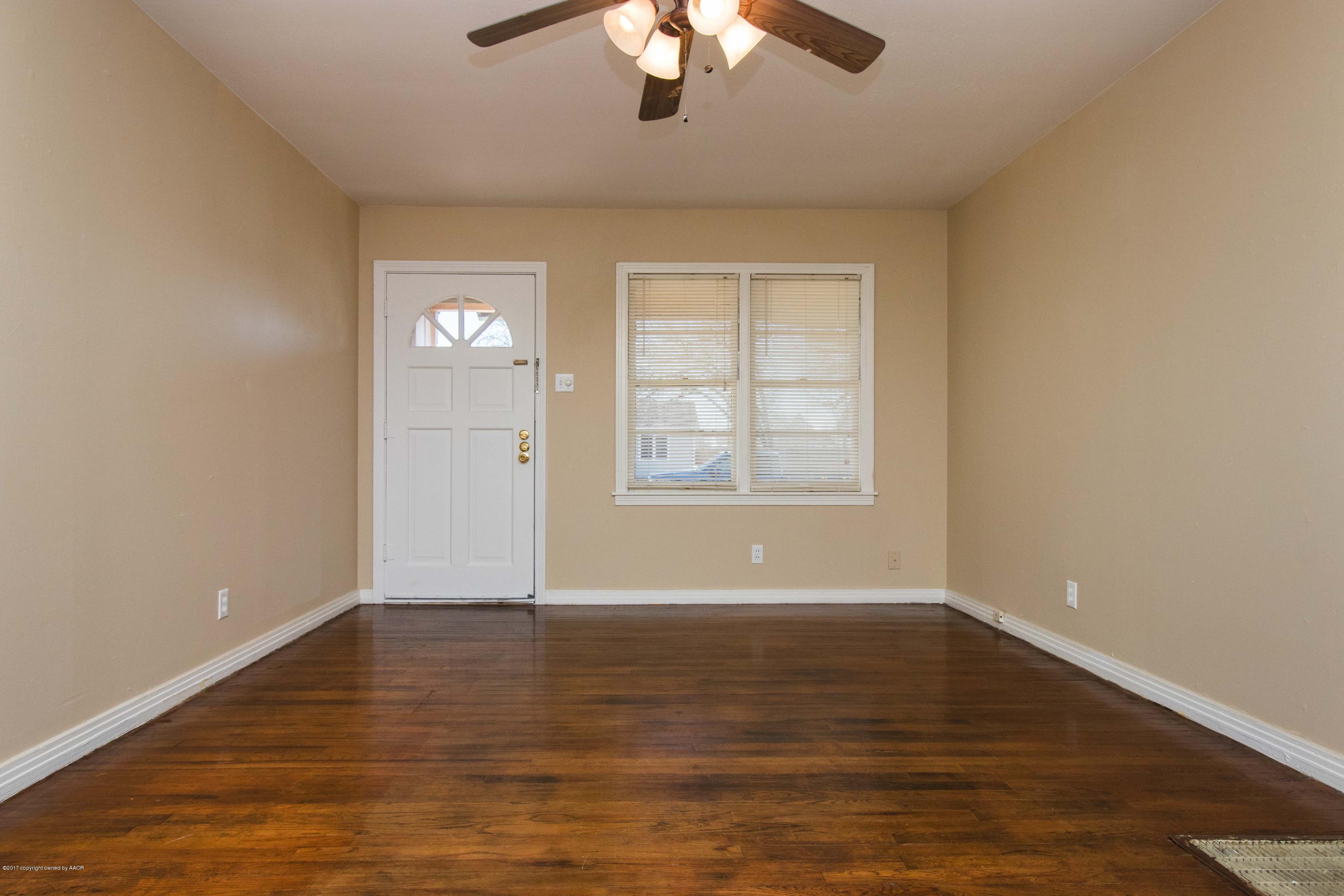 4314 Parker Street Amarillo, TX 79110 - Photo 4 of 20 an empty room with wooden floor chandelier fan and windows
