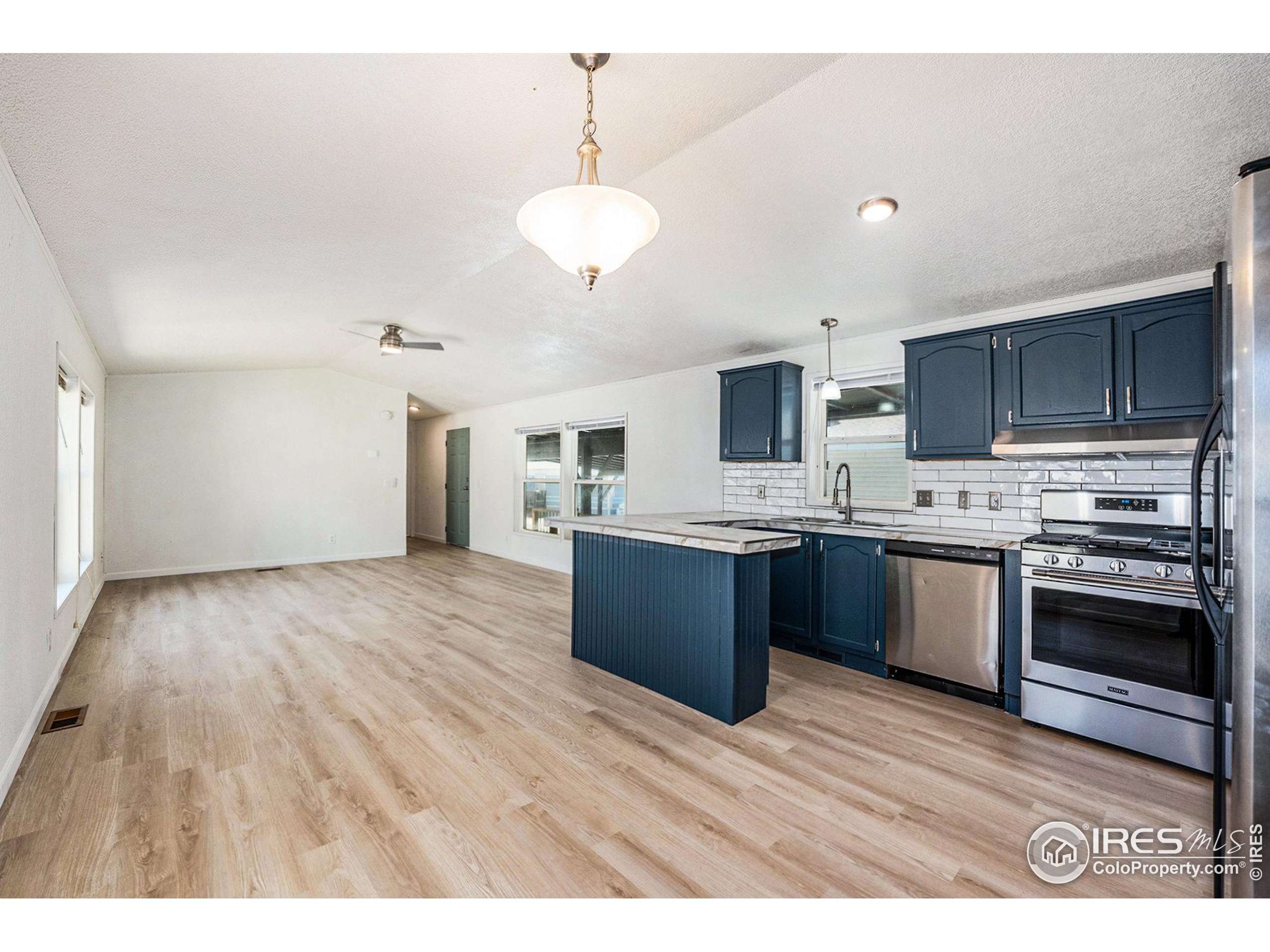 230 North 2nd Street, Unit 26 Berthoud, CO 80513 - Photo 8 of 21 a large kitchen with stainless steel appliances granite countertop a stove a sink dishwasher and a oven with wooden floor