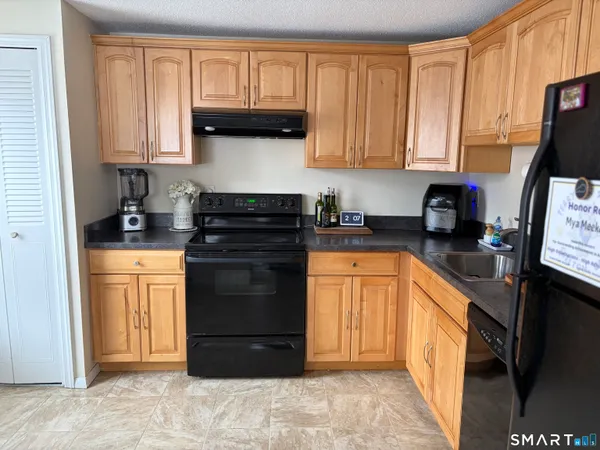 a kitchen with stainless steel appliances granite countertop a stove top oven a refrigerator a sink and dishwasher with wooden floor