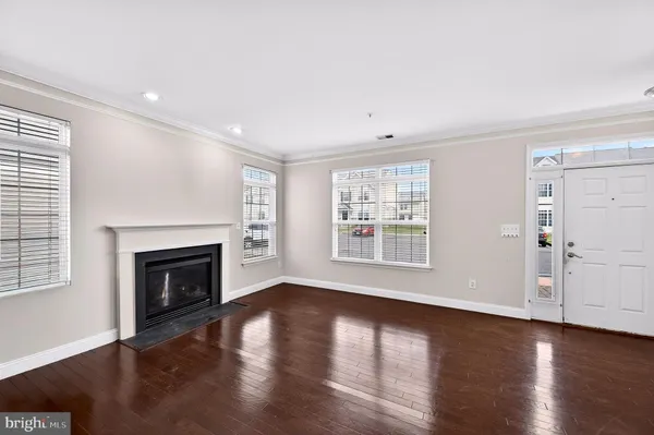 an empty room with wooden floor fireplace and windows