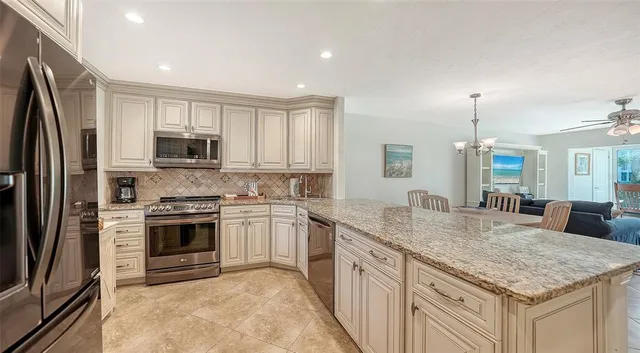 a kitchen with stainless steel appliances granite countertop a refrigerator a stove and a sink with wooden floor