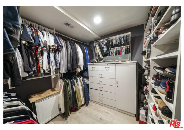 a view of walk in closet with clothes and shoes