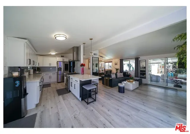 a living room with lots of wooden furniture dining table wooden floor and a large window