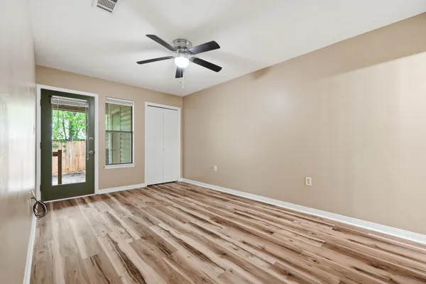 a view of an empty room with wooden floor and a window