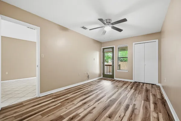 a view of an empty room with wooden floor and a window