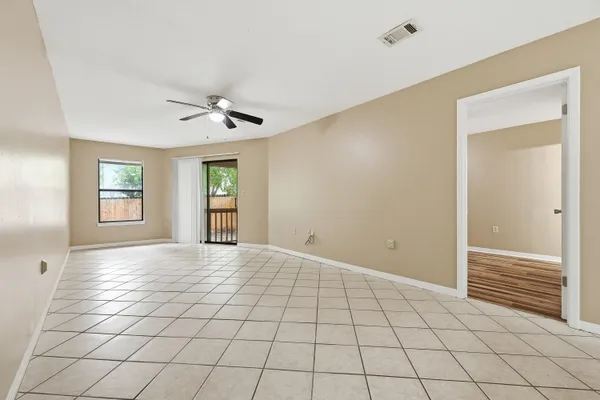 a view of an empty room with window and chandelier fan
