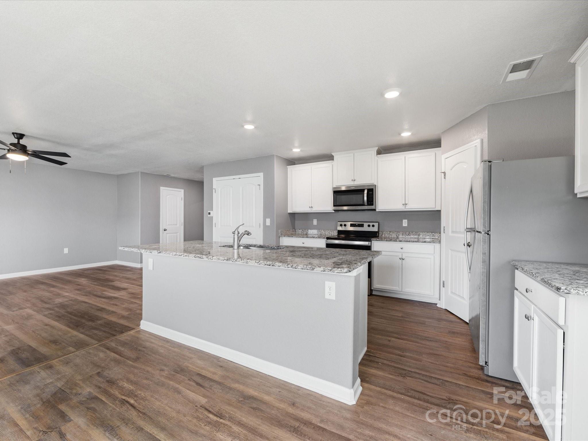 9136 Creedmore Hills Drive Charlotte, NC 28214 - Photo 13 of 48 a large kitchen with kitchen island a sink a stove a refrigerator and white cabinets with wooden floor