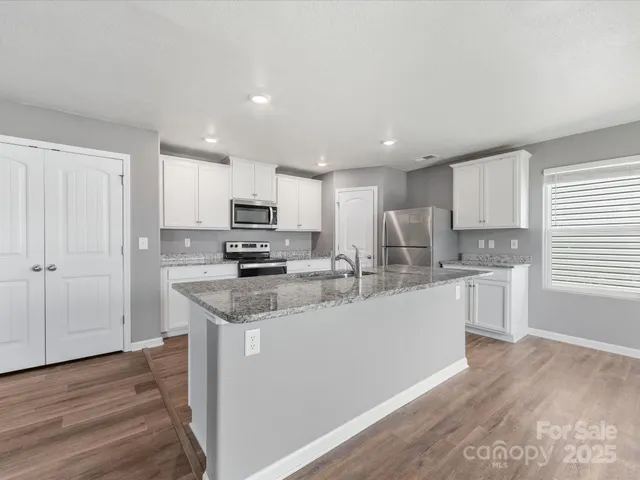 a kitchen with stainless steel appliances granite countertop a sink refrigerator and cabinets
