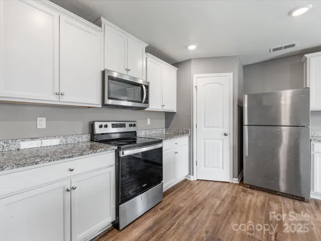 a kitchen with granite countertop a refrigerator stove and microwave