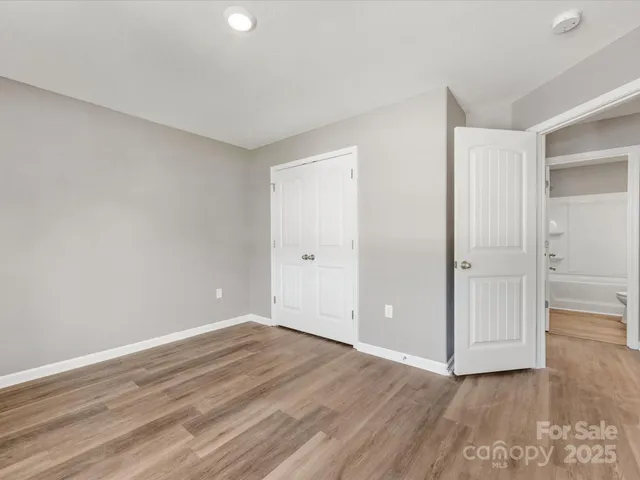 a view of an empty room with wooden floor and closet