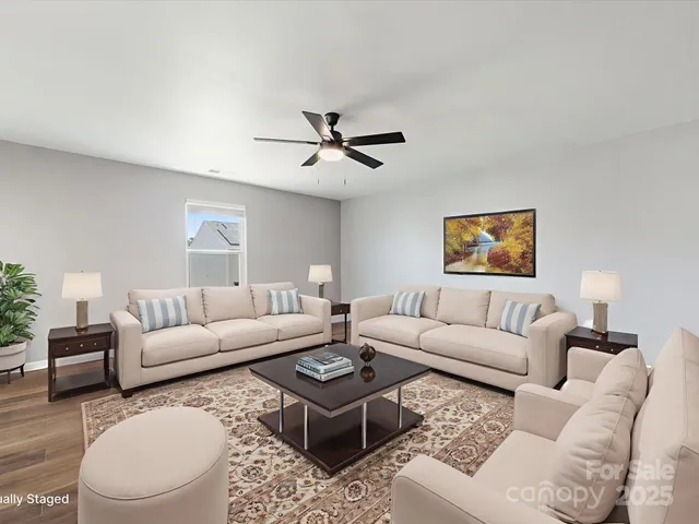 a living room with furniture a ceiling fan a lamp and a window