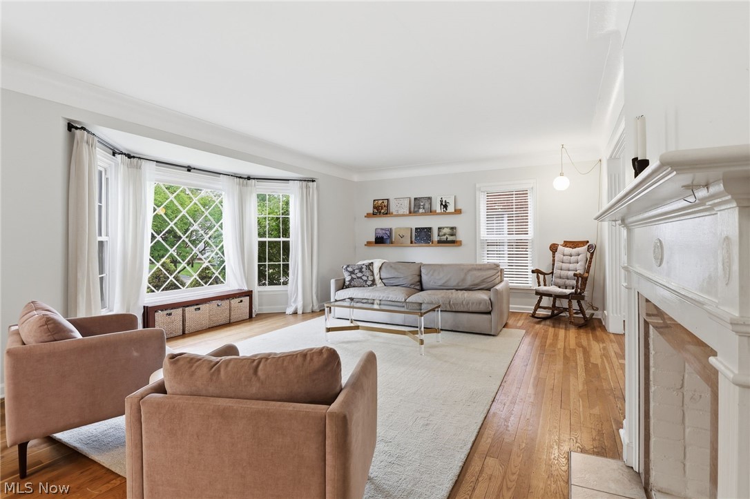 3713 Winchell Road Shaker Heights, OH 44122 - Photo 4 of 38 Living area featuring a prominent bay window with diamond-pane grilles, hardwood flooring, a white mantelpiece, overhead ceiling lighting, and built-in floating shelves