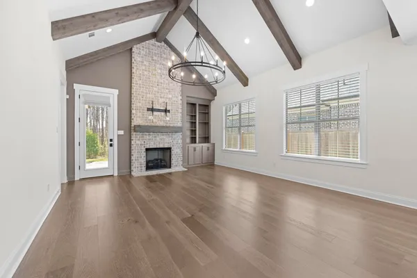 an empty room with wooden floor fireplace and windows