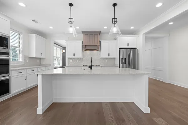 a large kitchen with granite countertop a sink cabinets and stainless steel appliances