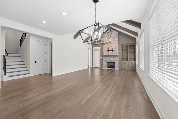 a view of a livingroom with wooden floor staircase and a kitchen space