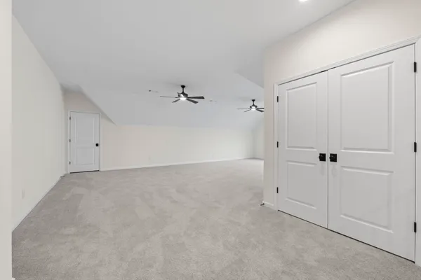 an empty room with chandelier fan and windows