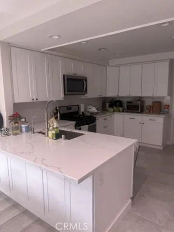 a kitchen with granite countertop a sink a stove top oven a counter top space and cabinets