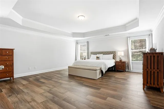 a bedroom with a bed and dresser with wooden floor