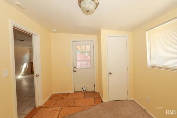 an empty room with a chandelier fan and a window