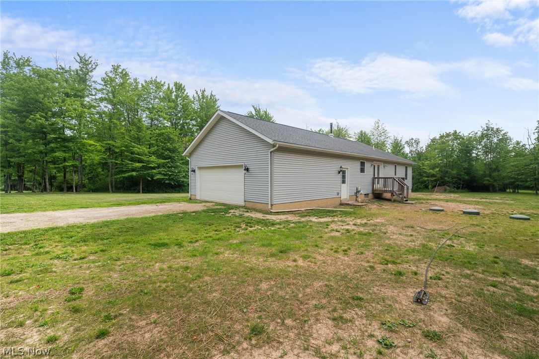 16985 Moseley Road Thompson, OH 44086 - Photo 19 of 22 View of side of home featuring a garage and a lawn