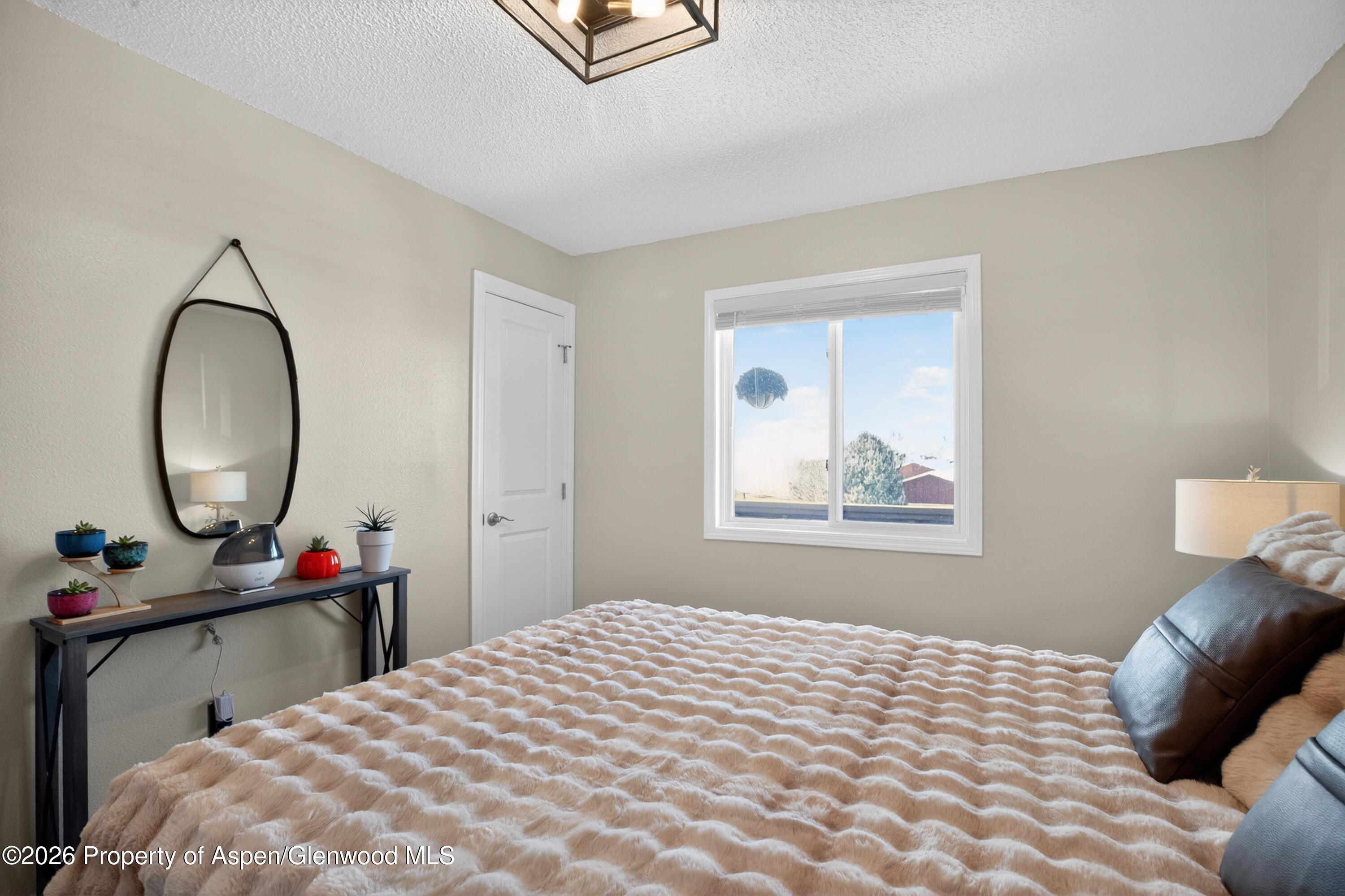1310 Dogwood Drive Rifle, CO 81650 - Photo 21 of 49 a bedroom with a bed a mirror and a window
