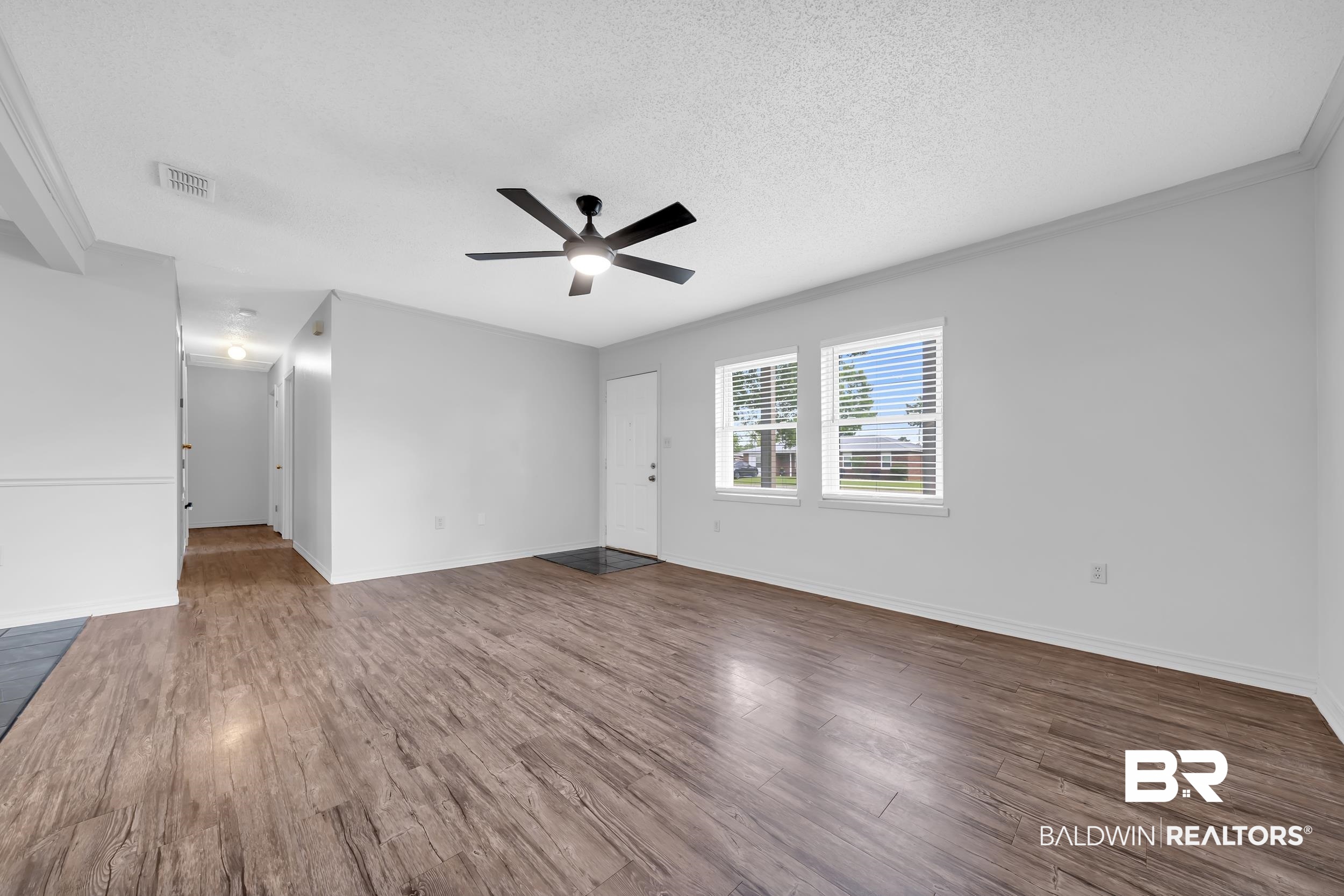 421 Cedar Court Foley, AL 36535 - Photo 13 of 39 Spacious living area featuring wood-finish flooring, two large windows with horizontal blinds, a modern ceiling fan, and crisp white walls