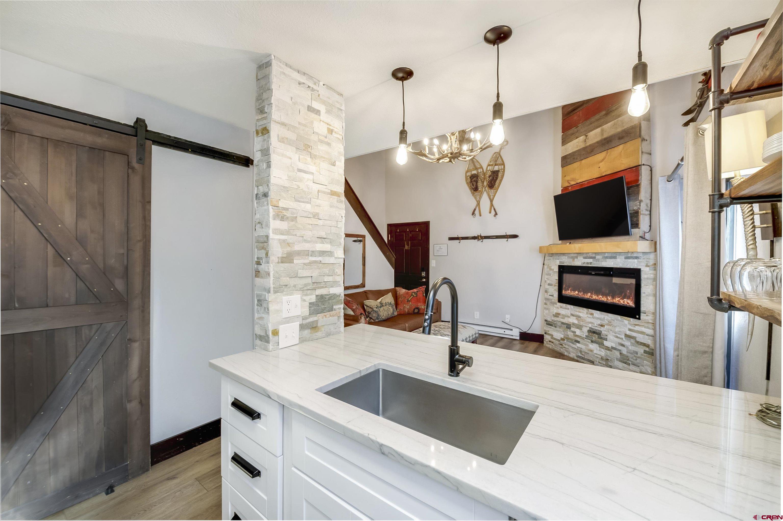 11 Emmons Road, Unit 430 Crested Butte, CO 81225 - Photo 7 of 27 a kitchen with a sink a faucet a fireplace and wooden floor