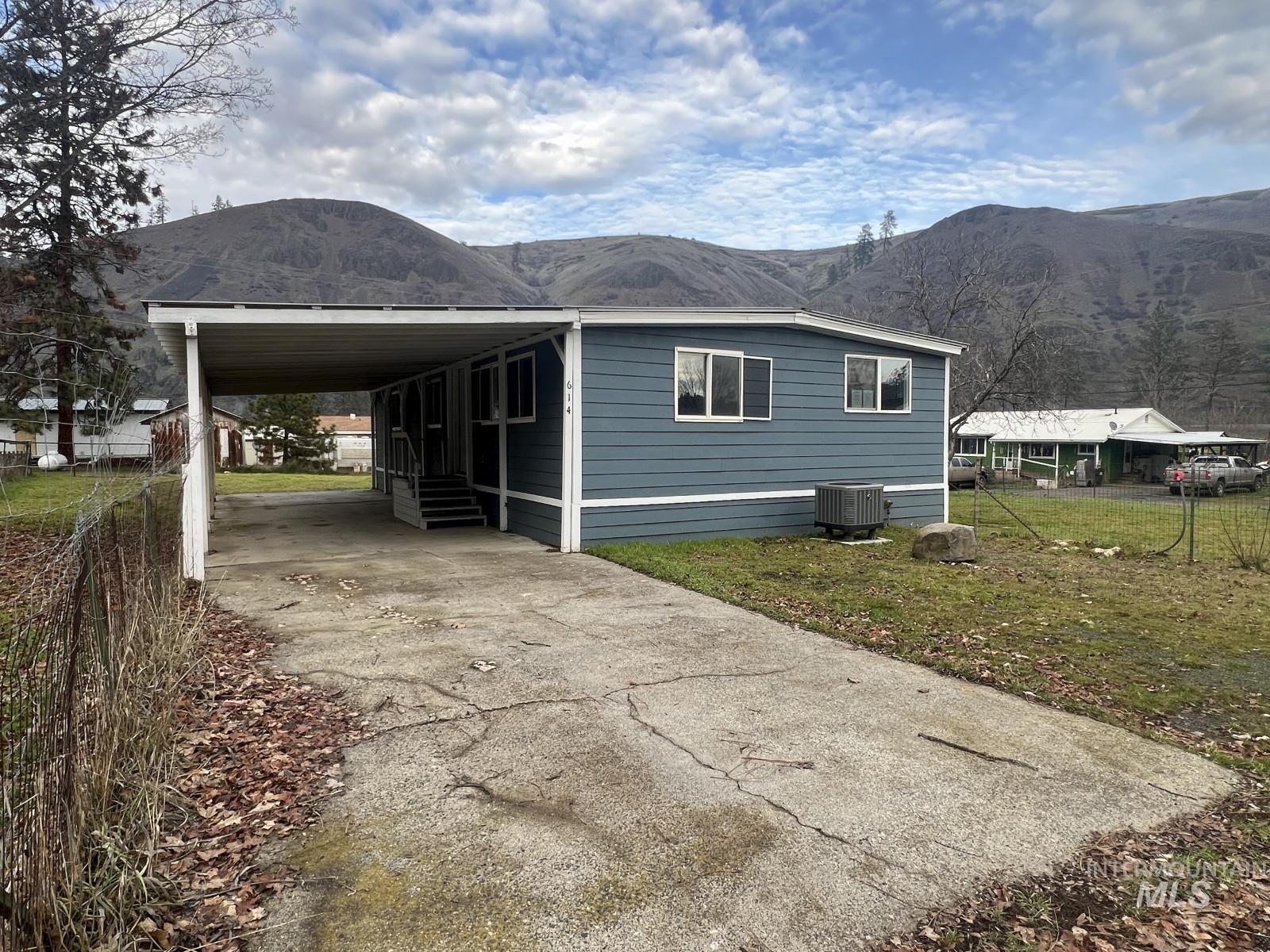 614 Pine Avenue Kooskia, ID 83539 - Photo 20 of 27 View of home's exterior featuring concrete driveway, a mountain view, a carport, and entry steps