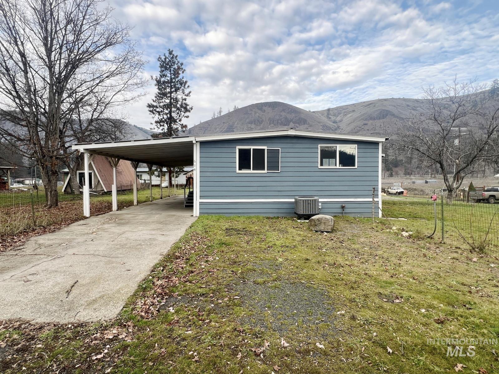 614 Pine Avenue Kooskia, ID 83539 - Photo 2 of 27 View of property exterior featuring driveway, a lawn, a carport, and a mountain view
